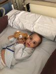 Niño en cama de hospital con un oso de peluche