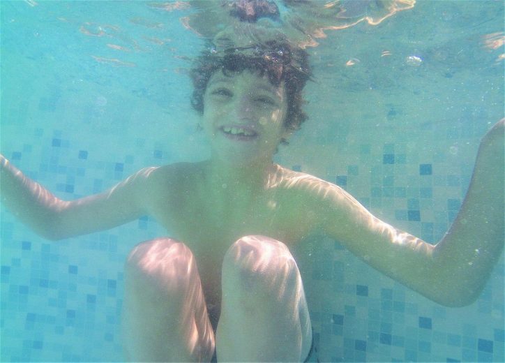 Foto tomada bajo el agua. Rodrigo bucea y sonríe. Estimulando en verano