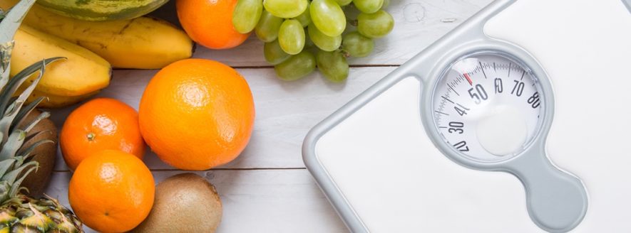 Fruta al lado de un peso para control de obesidad
