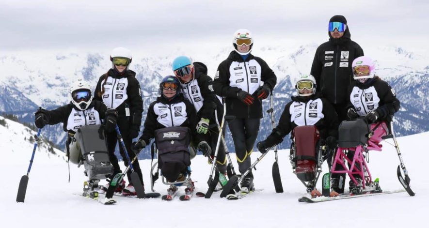 GHrupo de niños y adultos haciendo Esquí adaptado